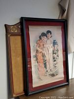 Framed Asian style wall art of two women golfing leaning against wall showing the overall frame and partial detail.