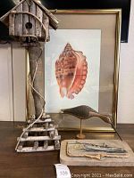 Photo showing the rough wood birdhouse, framed shell print, wooden bird sculpture, and nautical boat art grouped together