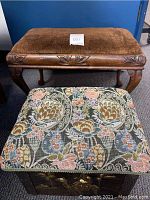 Two footstools positioned one behind the other to show size difference, upholstery, and carved details of the larger footstool