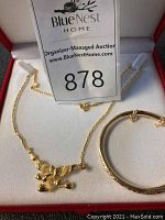 Necklace and bangle displayed together in velvet box under auction card
