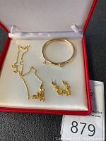 Overview of necklace, bangle bracelet, and earrings laid in presentation box