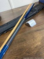 Full view of two-piece pool cue placed on table next to soft zippered black case