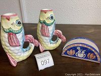 Wide shot showing two fish candleholders and one owl napkin holder on table.