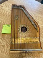 Photo showing entire zither mandolin on wood surface with ruler for scale and Lot 906 note.