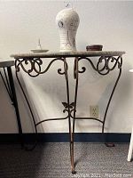 Full side view of hallway table showing wrought iron legs with butterfly accent and marble top.