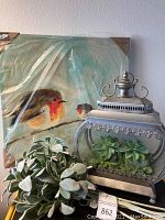 Photo of 24x24 bird artwork, artificial lambs ear stems, artificial succulents, and silver lantern terrarium showing the lot contents.