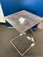 Full view of the under sofa side table showing the square top wrapped in plastic with mosaic pattern visible. Metal base with rubbed nickel finish and tag attached.