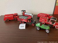 Overview of five Texaco diecast collectible vehicles including four red banks and one green race car, displayed on table.