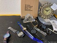 View of all included clocks and assorted wristwatches, showing four Waterford crystal clocks, the boxed amber gem clock, and six assorted watches.