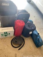 Wide view showing all items in the camping lot including suitcases, sleeping bags, first aid kit, inflatable bed and pump.