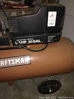 Side view of the Craftsman air compressor showing the 5.5 HP and 30 gallon labeling on the black motor housing and orange tank with wheels.