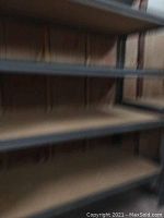 Close-up of two MDF shelves supported by metal frame against an unfinished wall.