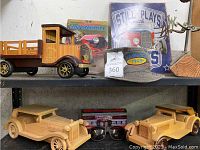 Full view of Ghirardelli & Sons wooden truck, two wooden vintage car models, two books, sunglasses, and weathervane on shelf