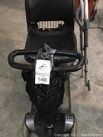 Front view of scooter tiller showing handlebar controls, key switch and front basket.