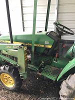 Left side view of tractor showing loader arm assembly, front wheel and steps to operator station