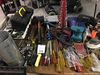 Wide angle view showing assorted hand tools including screwdrivers, socket stands, wrenches, and power tools on a work table.