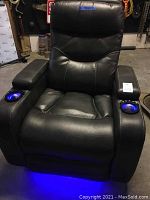 Front view of black leather power recliner with blue LED lights in cup holders and underneath glow.