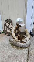 Front view of the resin boy birdbath sculpture showing the boy crouching next to the birdbath, with the dog statue and welcome sign behind.