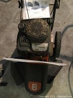 Top/front view of weed trimmer with manual placed on frame