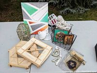 Overview of the lot contents including lanterns, milk glass candle holders, abstract painting, wall hangings, bracelet, scented candles, and assorted home decor