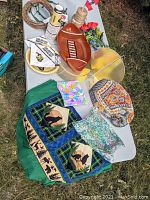 Photo showing assorted University of Colorado Buffalo party supplies including football-shaped tray, napkins, plates, green and blue forest-themed tablecloth with animal designs, craft supplies such as jute rope, wire wreath form, faux florals, and embroidered insulated elephant teapot cover.