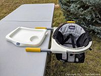 Chicco 360 Hook-On High Chair with white snap-on serving tray resting on table outdoors