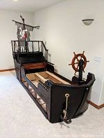 Front-angle view of the assembled bed frame showing hull shape, mast, sail and wheel.