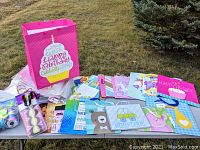 Full view of assorted colorful gift bags displayed outdoors with curling ribbons and tape on one side.