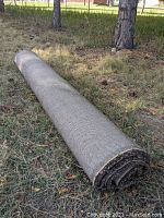 Rolled Ikea Adum rug brown gray colors on grass outdoors