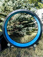 Assembled One Fast Cat exercise wheel outdoors with base on grass in front of trees.