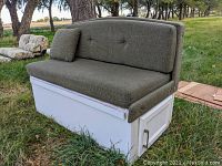 Side view of RV dining bench with green cushion and built-in storage cabinet with door and metal handle.