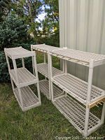 Two white plastic shelving units with four grid shelves each, shown outdoors and stacked side-by-side.