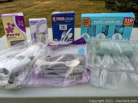 Various boxes and plastic bundles of disposable white plastic cutlery including spoons, forks, and knives on a table.