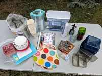 Photo showing entire collection on white table with disposable cups, water pitcher, coloring set, and other kitchenware