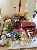 Wide shot showing the entire collection with pillar candles, red mosaic candle holder, assorted tins, and tea lights.