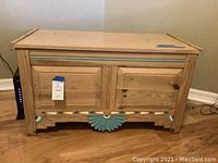 Front view of wooden file cabinet bench with decorative teal trim on lower front panel and hinged top closed.