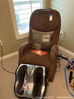 Brown massage chair and silver/black foot massager in a room