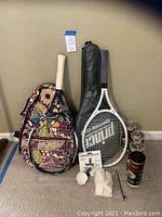 Complete lot showing two tennis rackets, their cases, tennis balls, accessory wristbands, and manual.