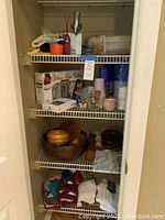 Photo of kitchen shelving showing wood salad bowls, kitchen towels, oven mitts, disposable cups, and utensils along with an Aerolatte frother and a cheese board