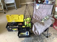 Overview of lot showing two toolboxes opened to reveal tools, basket with tennis balls, and folded chair