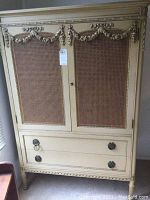 Front of armoire showing cane panel doors and bottom drawers