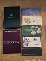 Overview of eight US Mint coin sets, showing various original packaging for years 1990, 1991, 1993, 1997, 1999 and Special Mint Set. Packaging includes plastic cases and cardboard holders in various colors and designs.