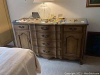 Full view of the wooden dresser showing its curved front with drawers and cabinets, and some items placed on top.