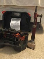 Black & Decker planer in its black and red carrying case alongside the metal bottle capper on the floor.