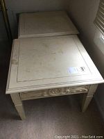 Pair of white painted wooden side tables with square tops. Top surfaces show water stains, discoloration, and scratches.