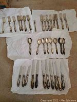 Full assortment of knives, forks and spoons arranged on white paper
