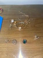 Overall lot arranged on wood surface showing watch, bracelets, necklace, and rings