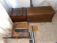 Vintage paper cutter with wooden base and metal cutting arm along with wooden boxes visible to the side