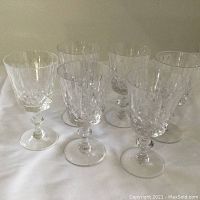 Group of six Edinburgh Crystal wine glasses with fine cut crystal patterns on a white surface.