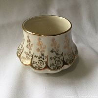 Close-up photo of the sugar bowl showing decorative 22K gold floral pattern on cream porcelain with scalloped edge.